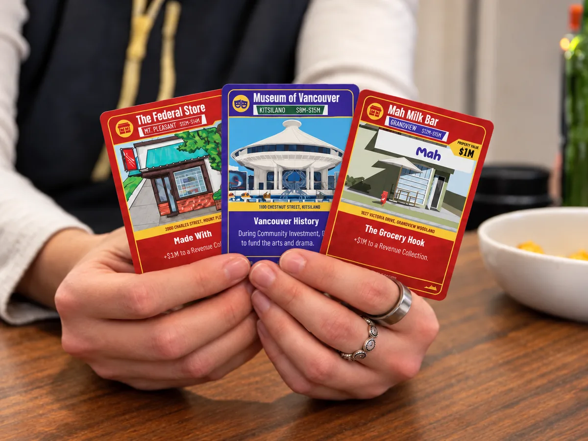 A pair of hands fanning three CityScape location cards above a table