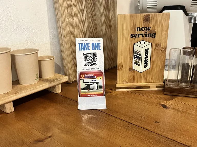 A CityScape card stand on a cafe counter, stocked with Mah Milk Bar cards